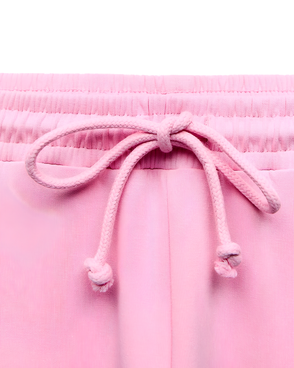 Close-up of a pair of light pink pants or shorts showing the elastic waistband and matching pink drawstring tied in a bow.