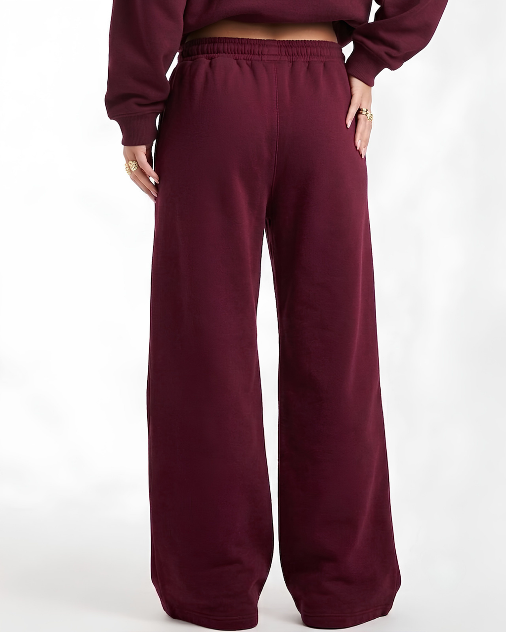A person wearing loose, wide-leg sweatpants in a deep burgundy or maroon color, shown from the back against a plain white studio background.