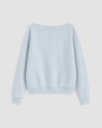A light blue crewneck sweatshirt shown from the back, featuring a wide boat neckline, long sleeves with ribbed cuffs, and a ribbed hem, displayed on a neutral light gray background.
