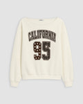 An off-white crewneck sweatshirt featuring a distressed varsity-style graphic on the front with the text 'CALIFORNIA' and the number '95' filled with stars.