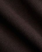 A close-up of dark brown knit fabric with soft diagonal folds showing the texture and weave.